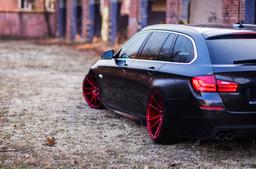 JR Wheels JR21 Red alloy wheel mounted on car in an atmospheric setting