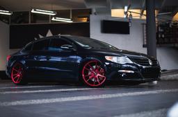 JR Wheels JR21 Red alloy wheel mounted on car in an atmospheric setting