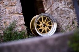 JR Wheels JR26 Gold alloy wheel mounted on car in an atmospheric setting