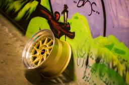 JR Wheels JR26 Gold alloy wheel mounted on car in an atmospheric setting