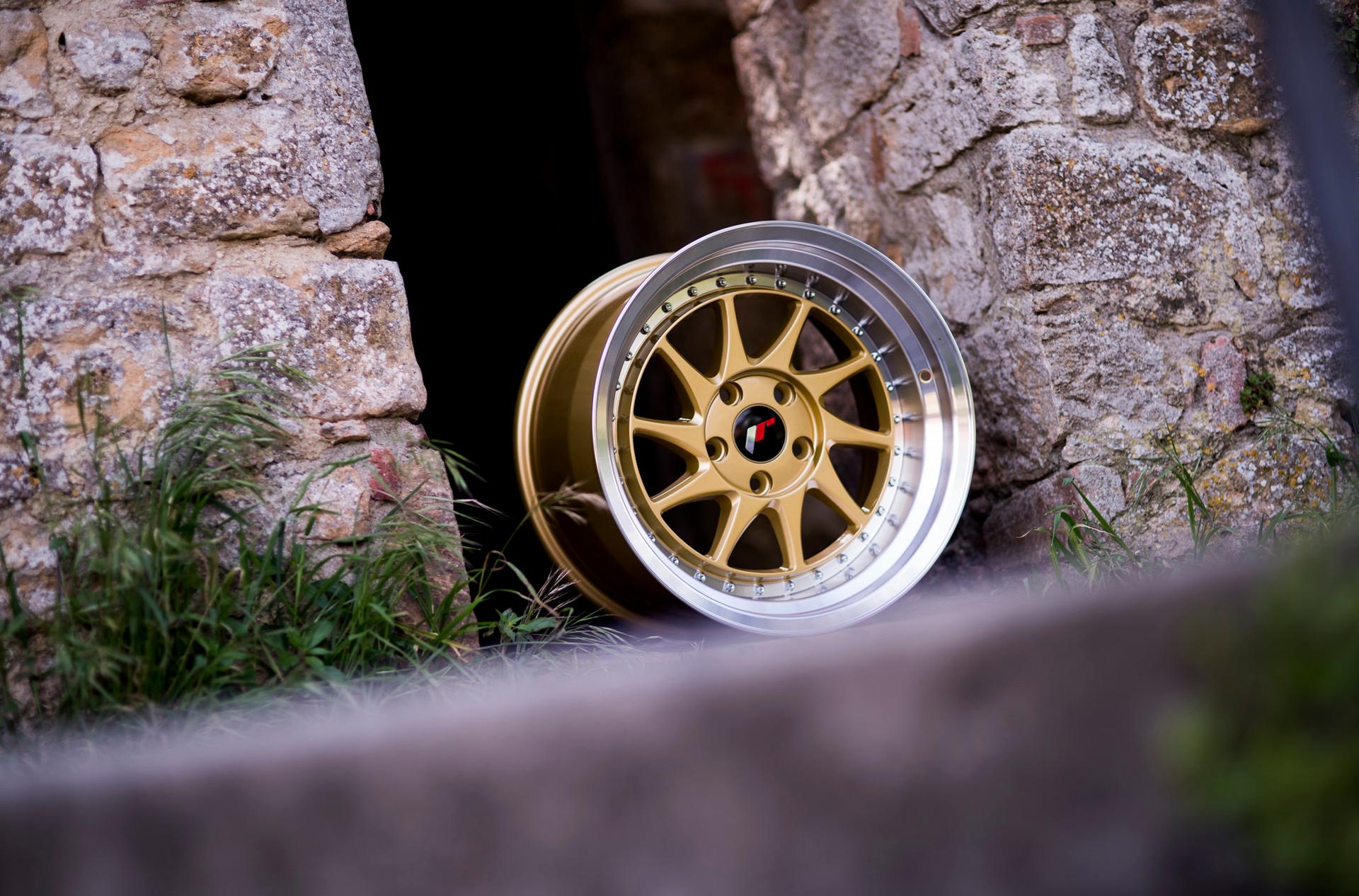 JR Wheels JR26 Gold alloy wheel mounted on car in an atmospheric setting