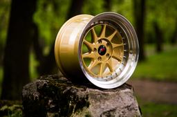 JR Wheels JR26 Gold alloy wheel mounted on car in an atmospheric setting
