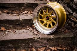 JR Wheels JR26 Guld aluminiumfälg monterade på bil i stämnigsfull miljö