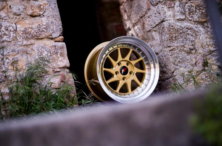 JR Wheels JR26 Gold alloy wheel mounted on car in an atmospheric setting