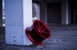 JR Wheels JR30 Röd aluminiumfälg monterade på bil i stämnigsfull miljö