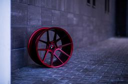 JR Wheels JR30 Röd aluminiumfälg monterade på bil i stämnigsfull miljö