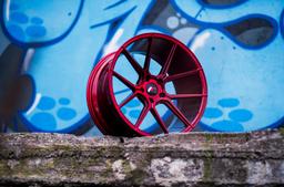JR Wheels JR30 Red alloy wheel mounted on car in an atmospheric setting