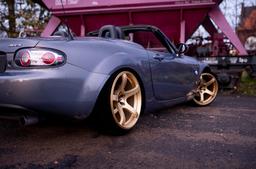 JR Wheels JR32 Gold alloy wheel mounted on car in an atmospheric setting