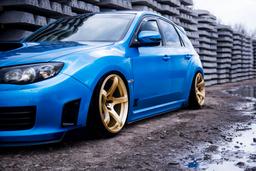 JR Wheels JR32 Gold alloy wheel mounted on car in an atmospheric setting