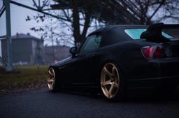 JR Wheels JR32 Gold alloy wheel mounted on car in an atmospheric setting