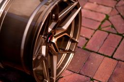 JR Wheels JR34 Bronze alloy wheel mounted on car in an atmospheric setting