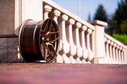 JR Wheels JR34 Bronze alloy wheel mounted on car in an atmospheric setting