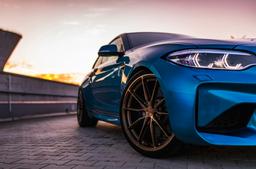 JR Wheels JR37 Bronze alloy wheel mounted on car in an atmospheric setting