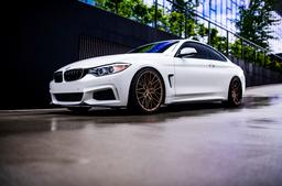 JR Wheels JR38 Bronze alloy wheel mounted on car in an atmospheric setting