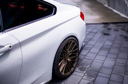 JR Wheels JR38 Bronse aluminiumsfelger montert på bil i en stemningsfull omgivelse