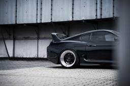 JR Wheels JR6 Black alloy wheel mounted on car in an atmospheric setting